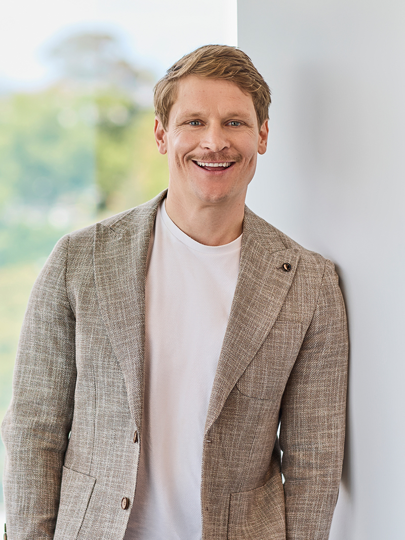 Individual wearing a light-coloured blazer over a white crew-neck top.