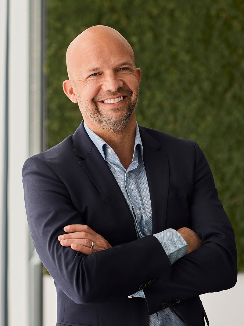 Individual wearing a dark blazer and light blue button-up shirt.