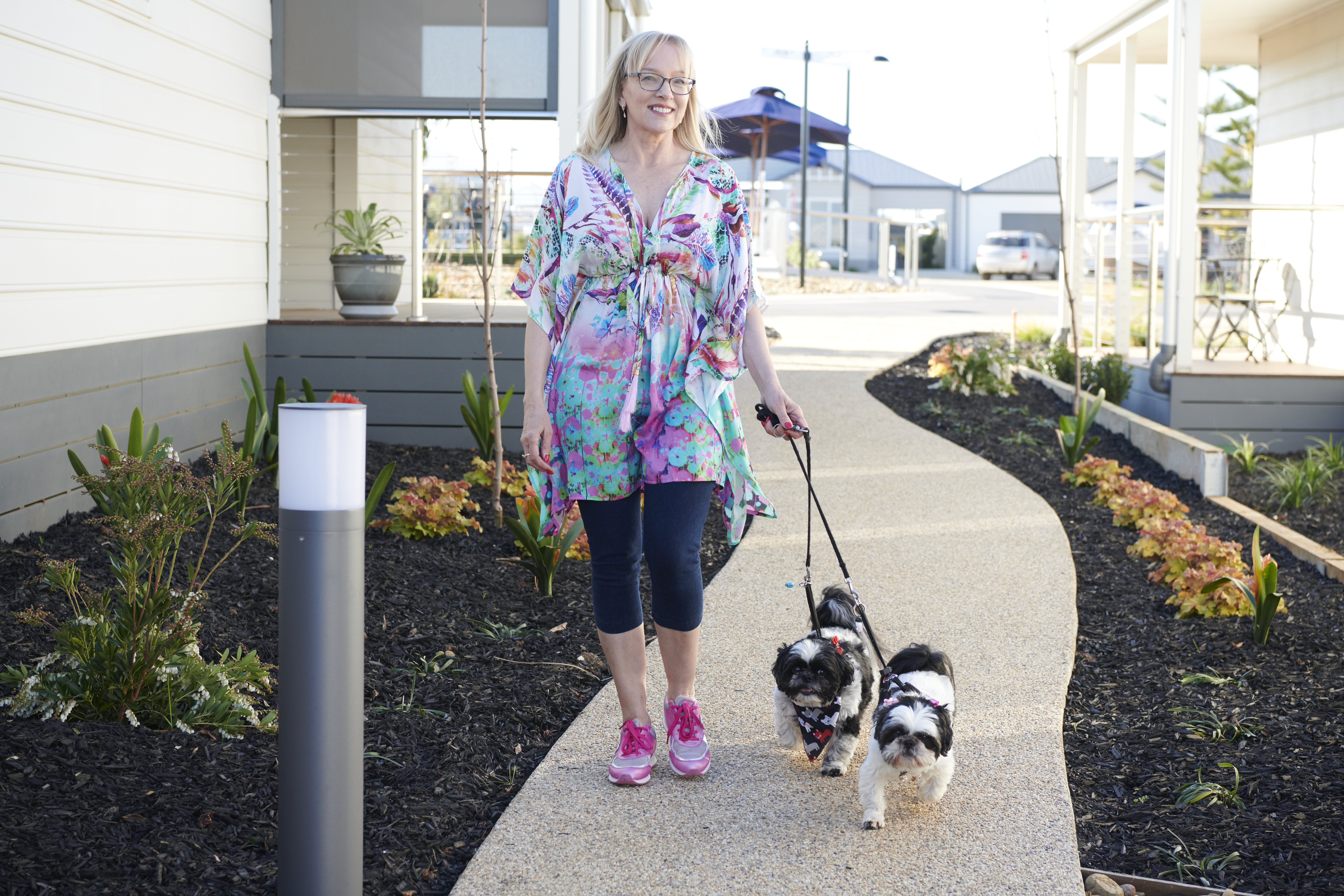 Resident walking her two small dogs along a garden pathway at Lifestyle Ocean Grove.