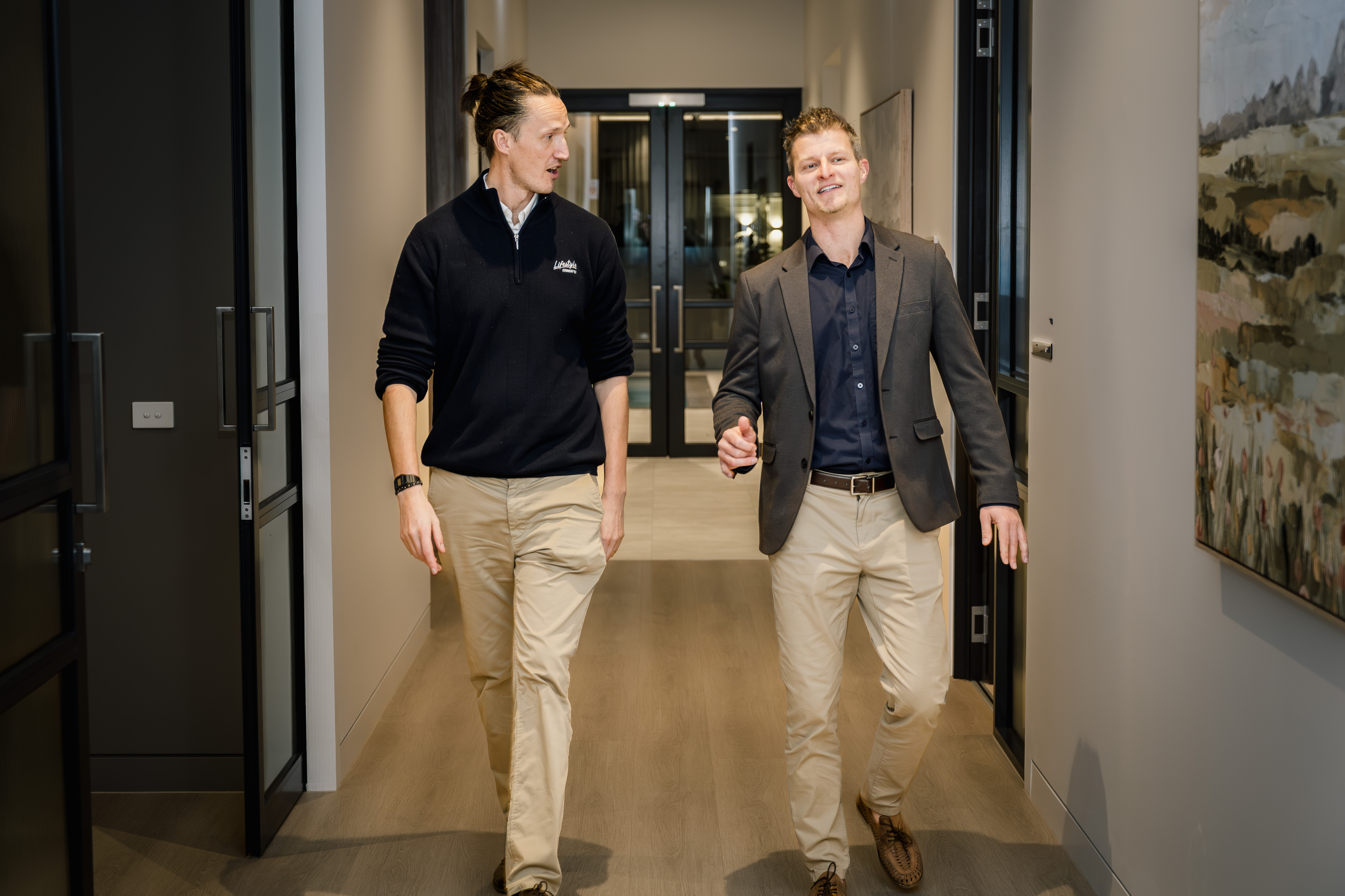 Lifestyle Communities team members walking and talking inside the clubhouse office corridor.