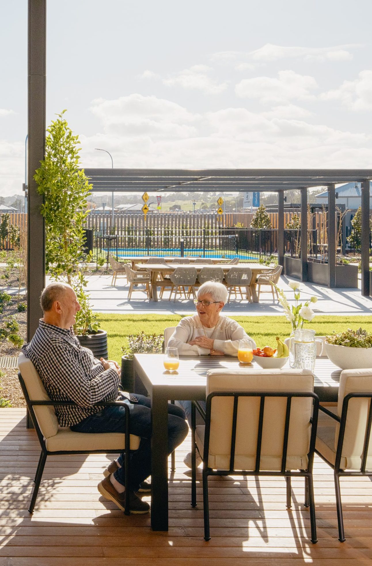 Couple relaxing outdoors with drinks on a sunny day at Lifestyle Ridgelea clubhouse deck.
