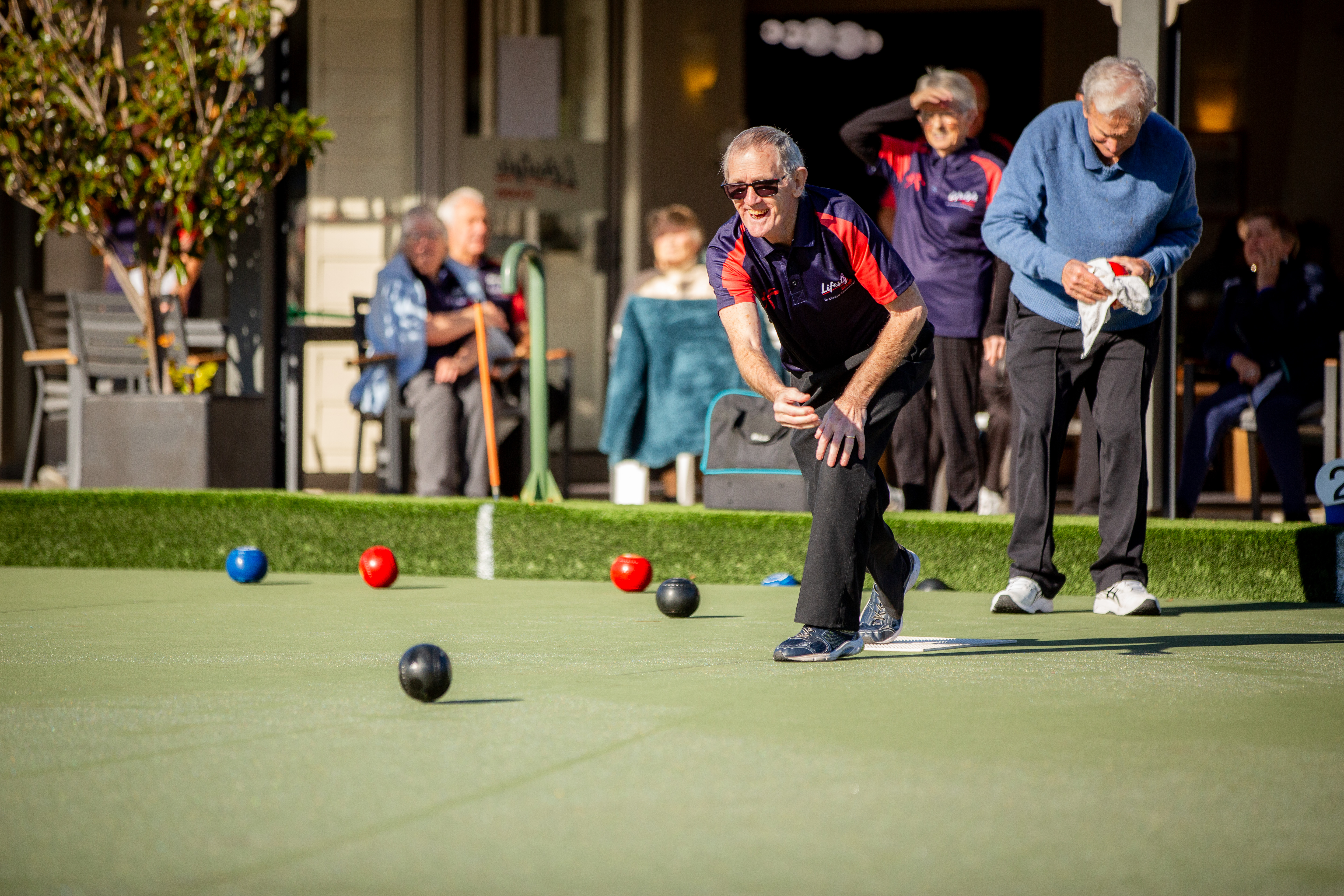 Group of friends playing lawn bowls together outdoors.