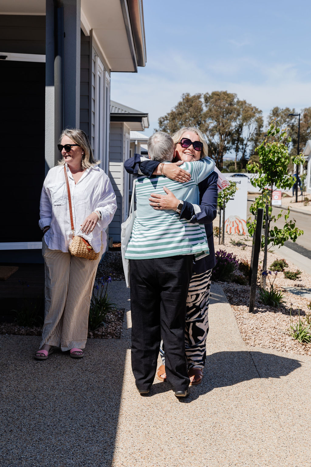 Residents greeting each other with a warm hug outside new homes at Lifestyle Communities.