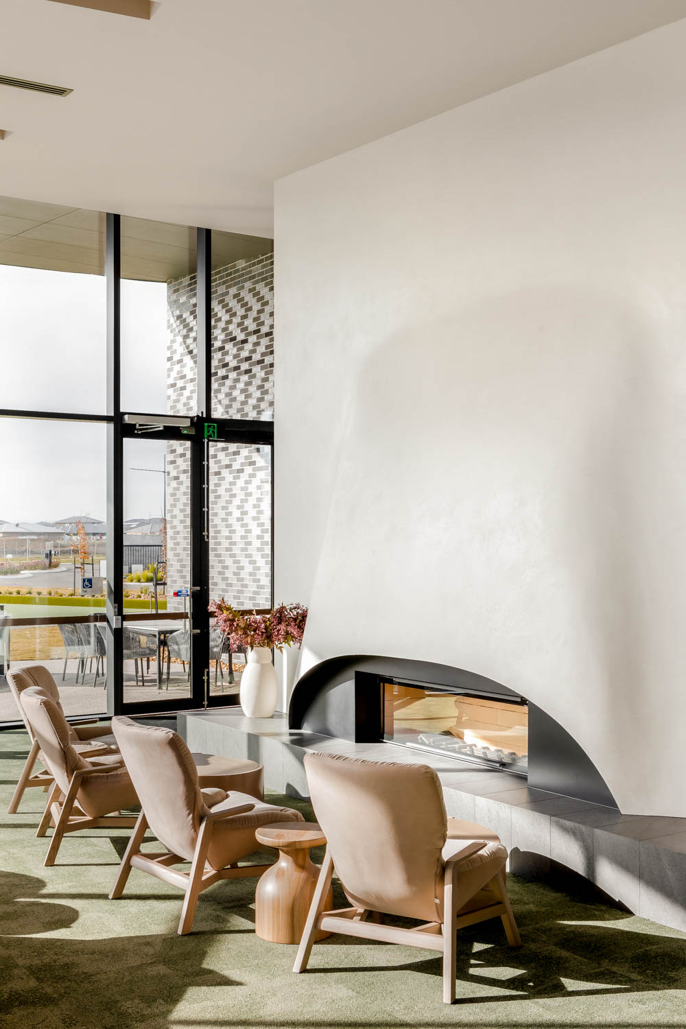 Modern fireplace lounge area with armchairs inside Wollert clubhouse.