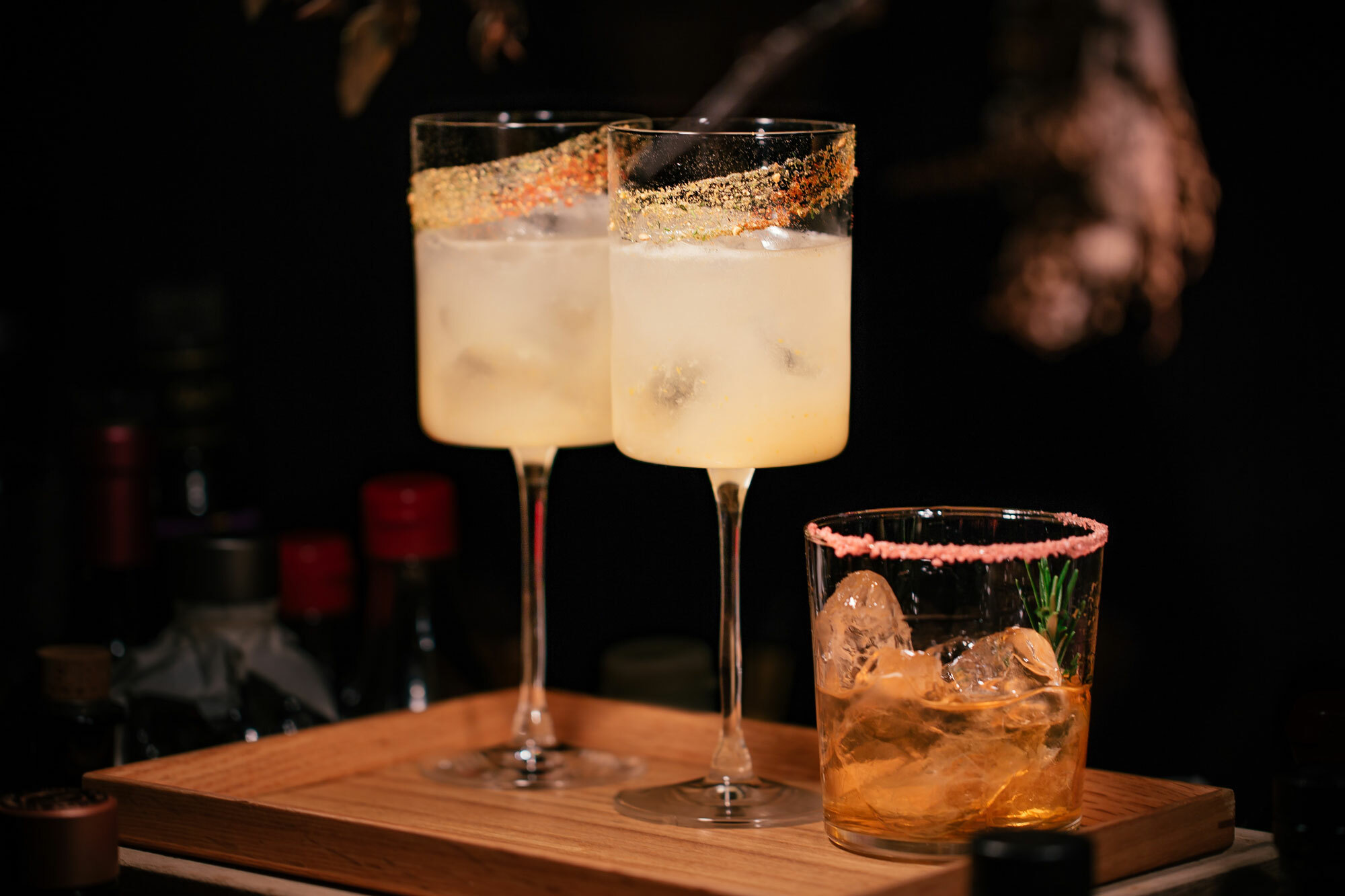 Three glass with beverages and garnishes.