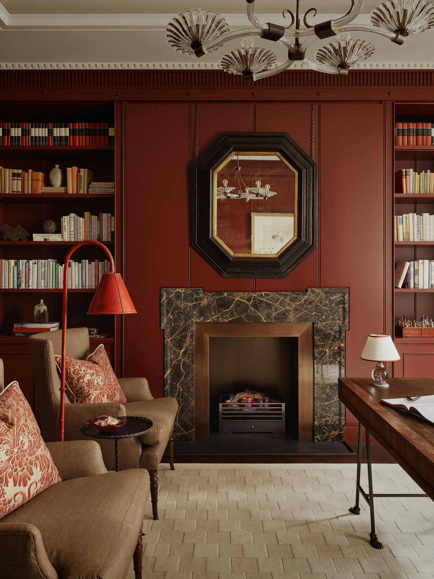 A lounge interior with dark walls, fireplace and furniture with fitted bookshelves.