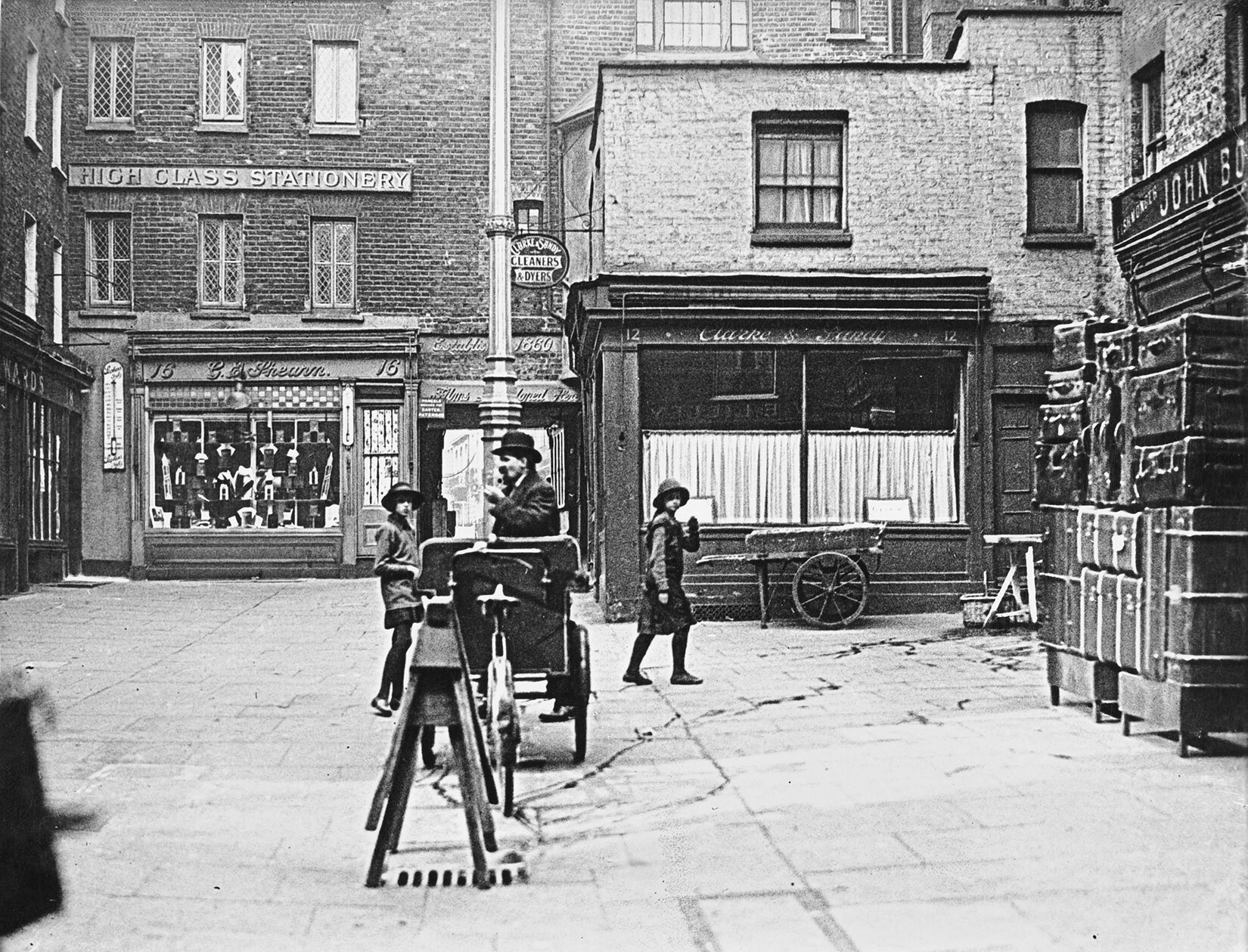 A black and white photograph of Shepherd Market in the 1900's with a few shops and people.