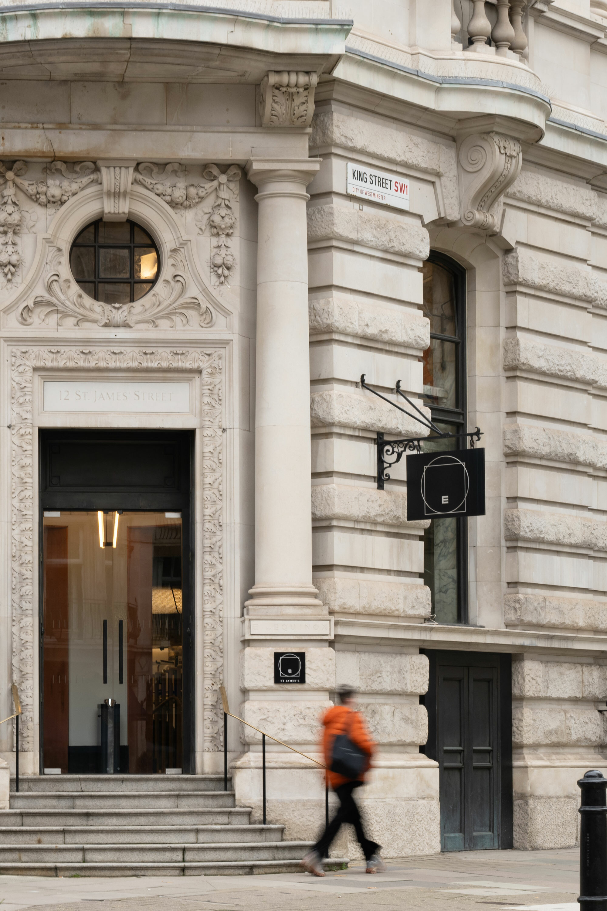 A corner view of Equinox Club with entrance stairs and person walking towards entrance.