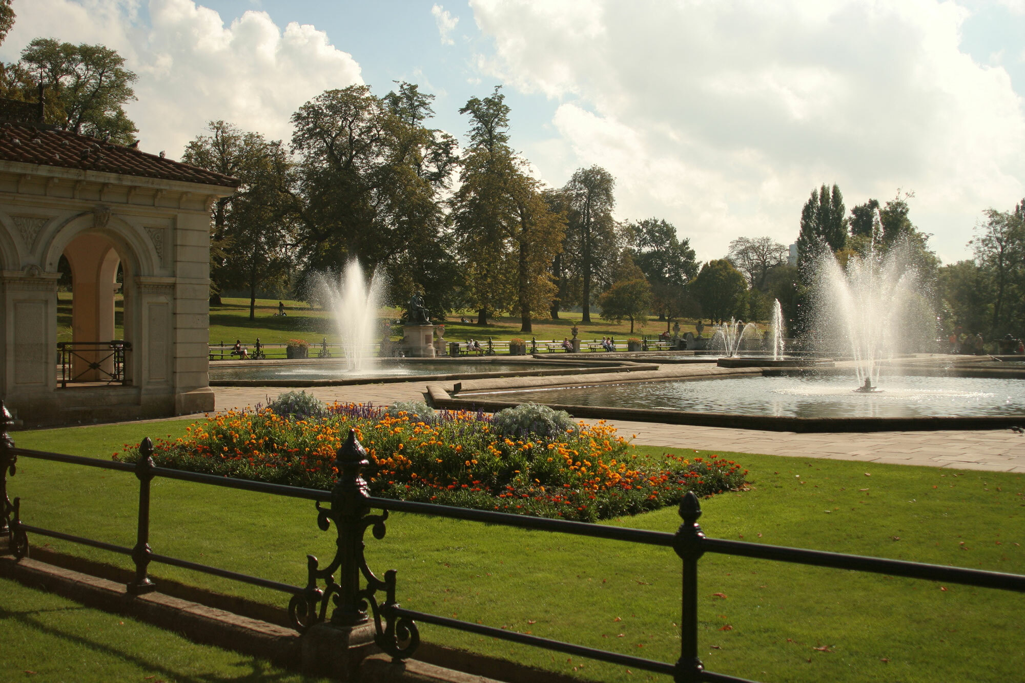 A view of Green Park with fountains, building and flowerbed and trees in the distance.