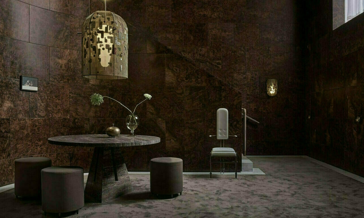 A grand tiled interior hall with tiled walls, floor table and large ceiling light fitting