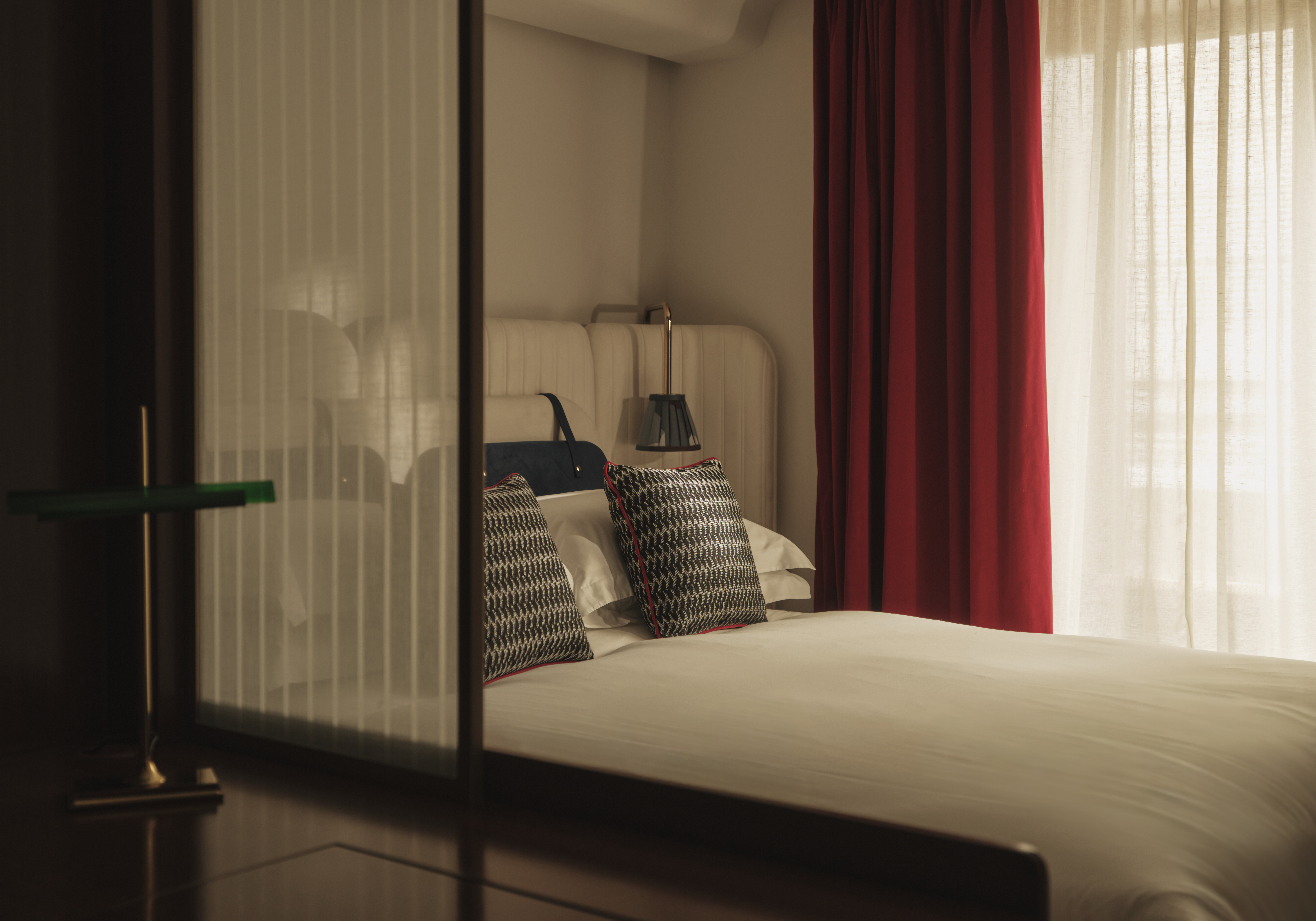 Chambre du Shepherd Mayfair avec rideau rouge et coussins à chevrons