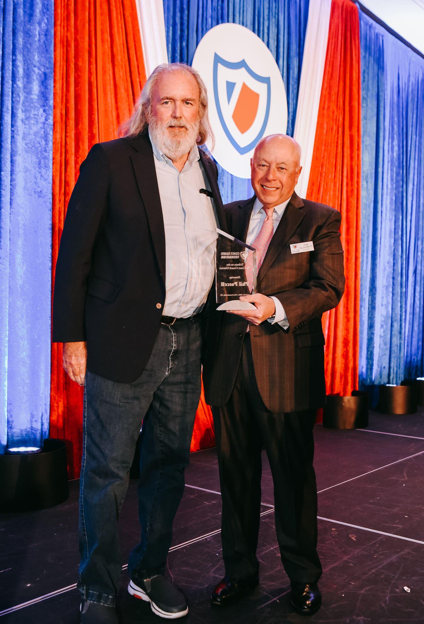 Two men pose for a picture on stage