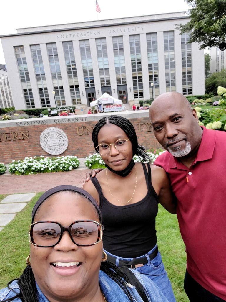 Three people pose for a selfie in front of an ornamental wall