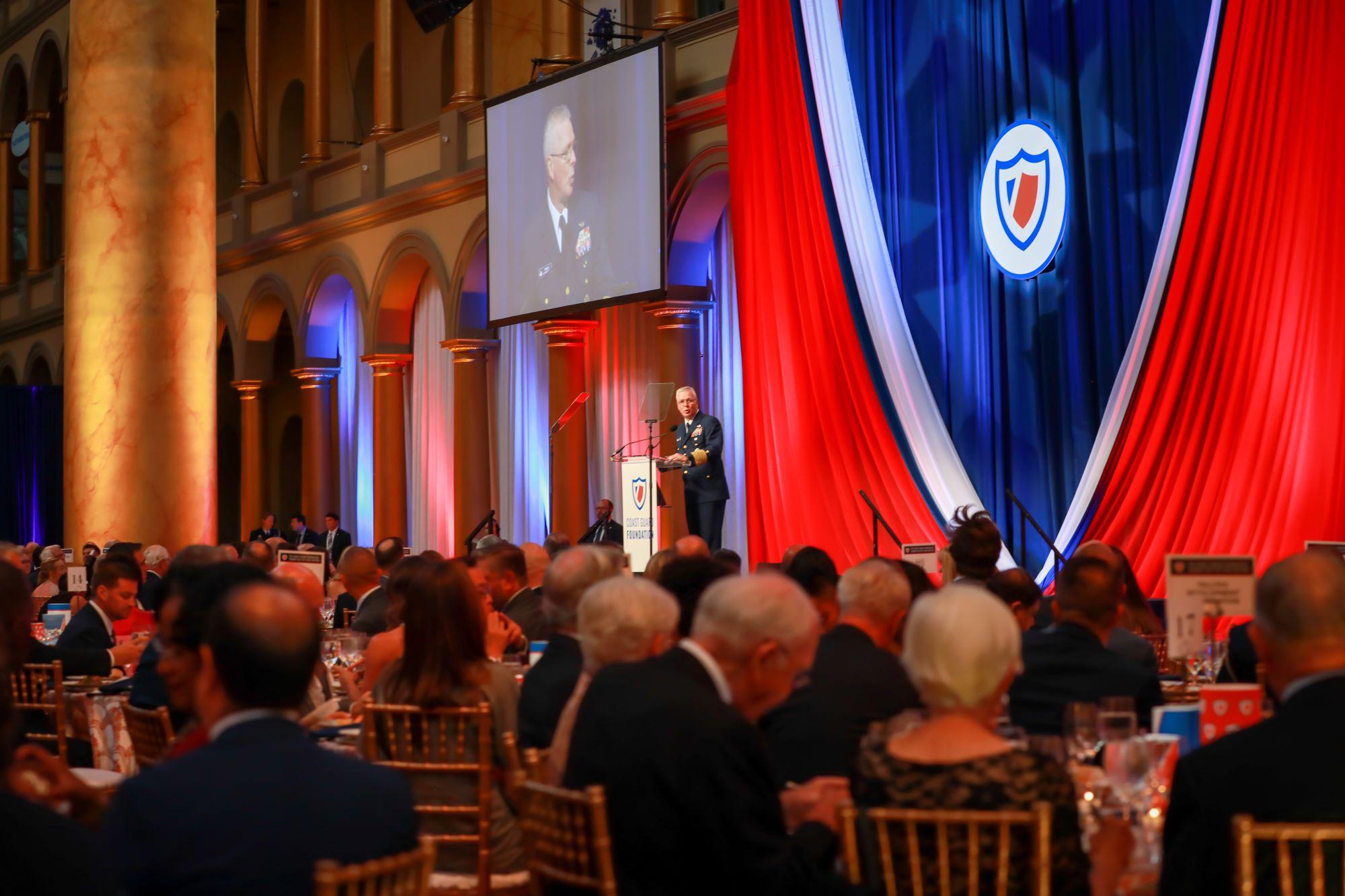 Coast Guard admiral at a podium on a stage