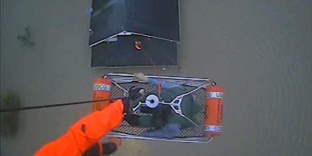 A person being hoisted into a Coast Guard helicopter.