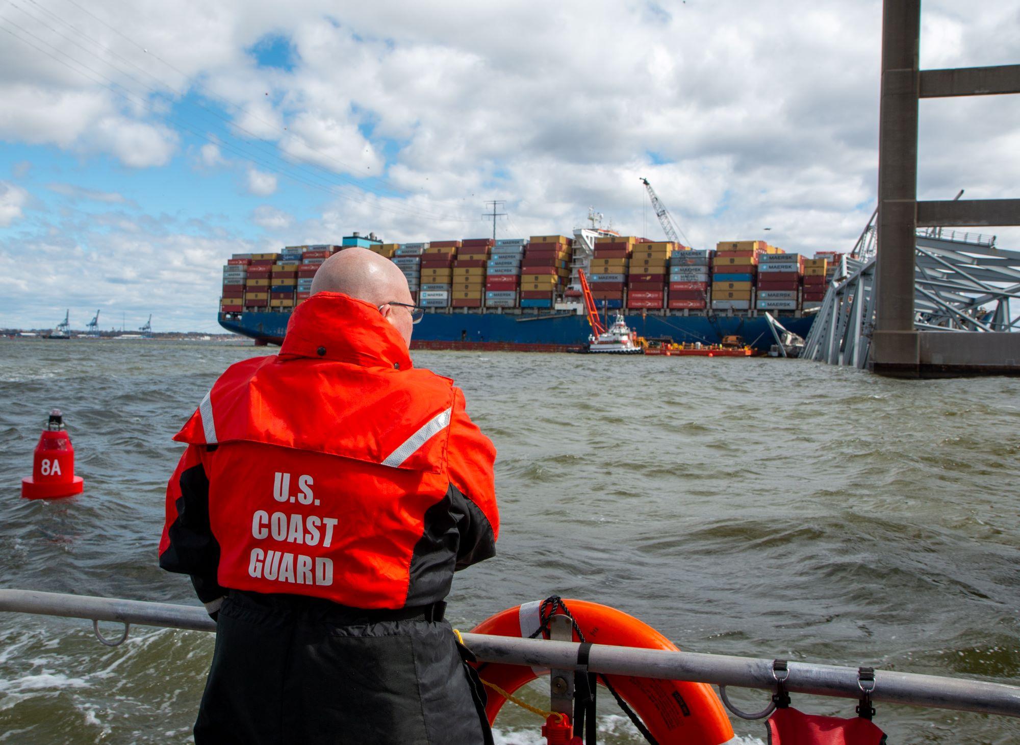 Man viewing wreckage of the Key Bridge from a Coast Guard boat.