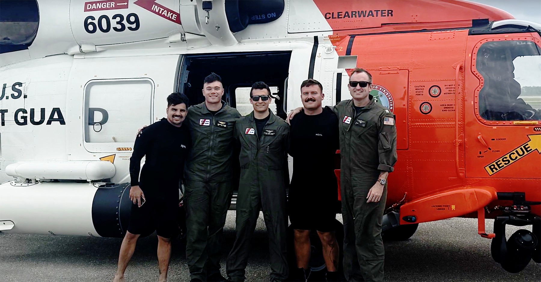 Coast Guard members standing in front of a helicopter