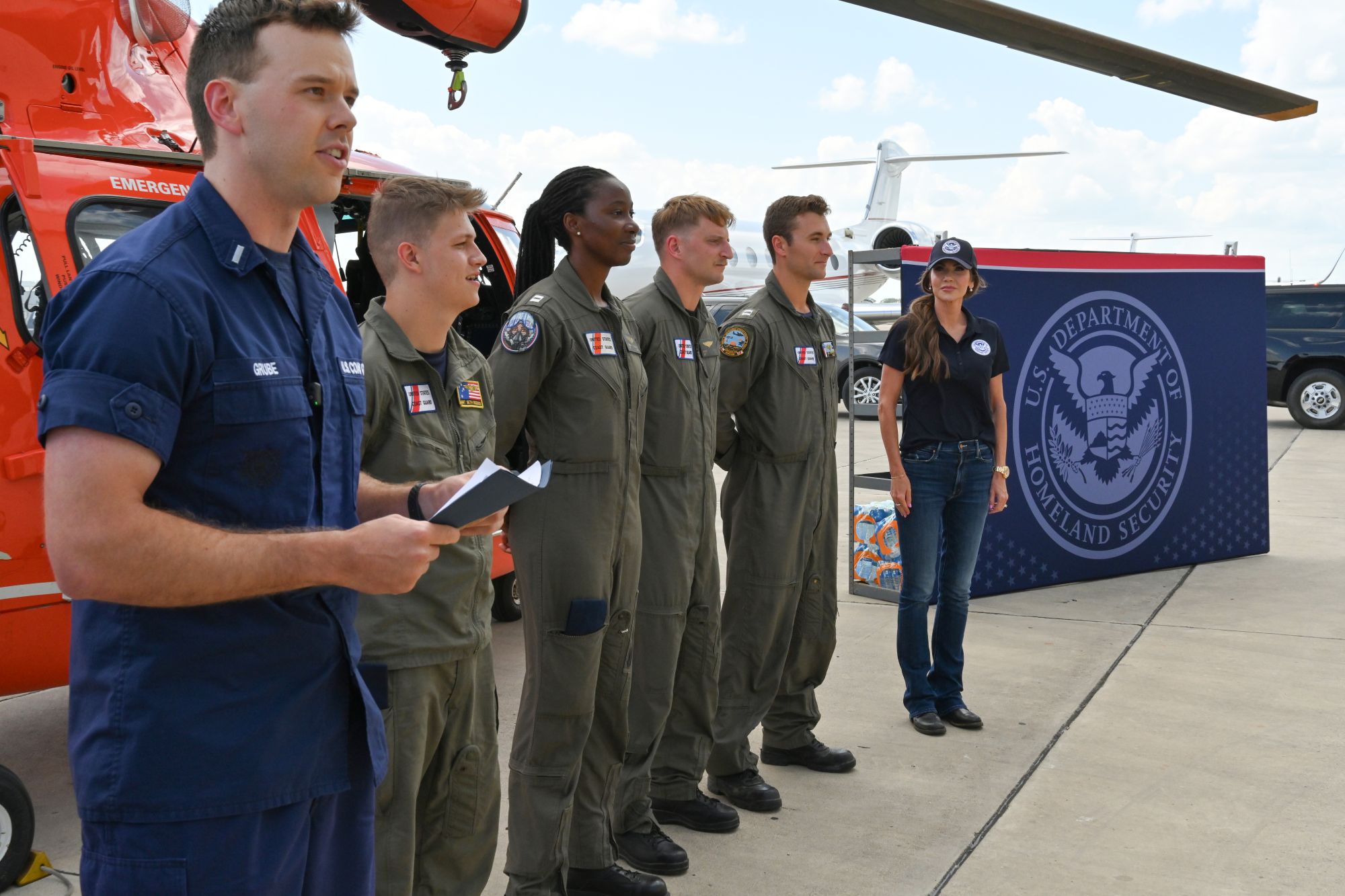 A Coast Guard Air crew stands in front of a helicopter