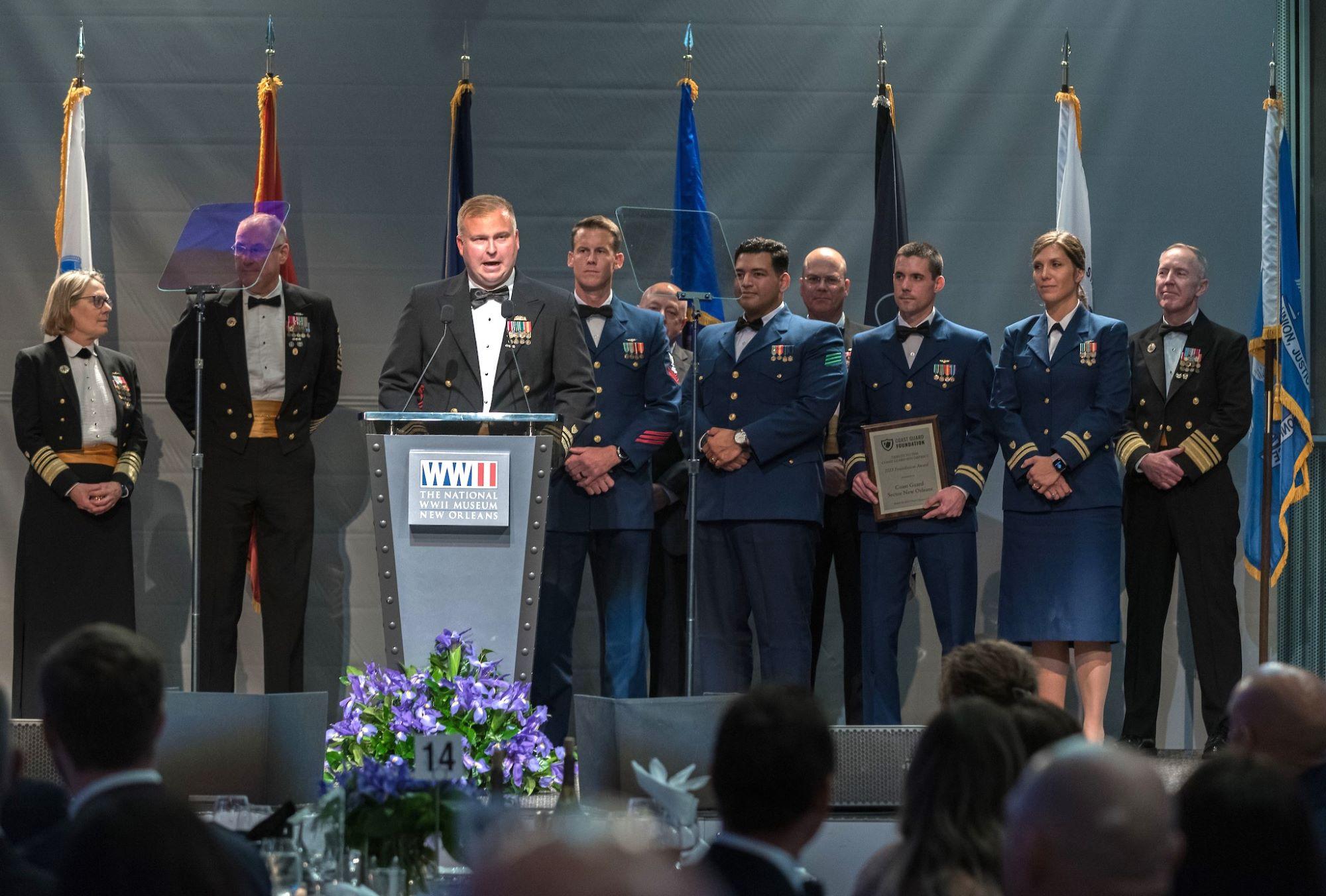 Coast Guard members stand on stage.