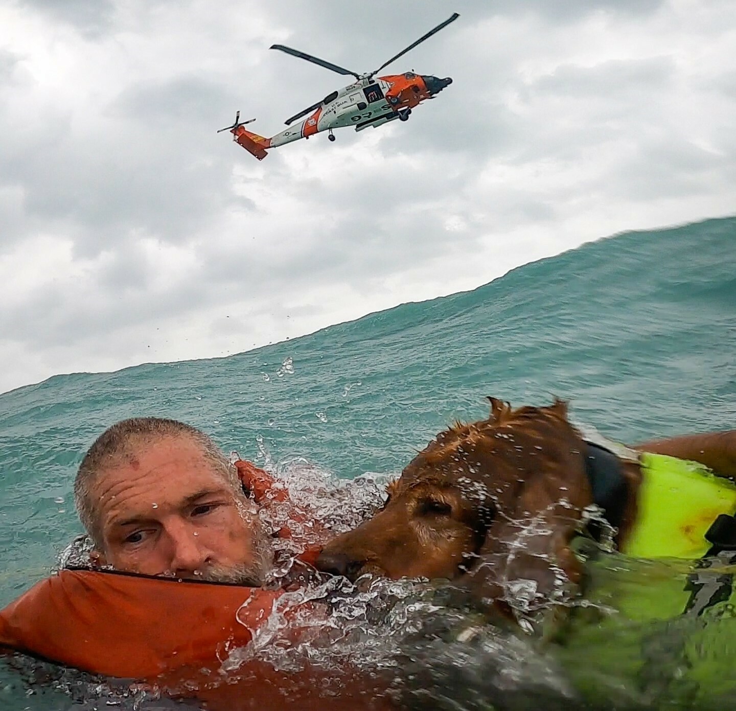 A man and dog with a helicopter hovering overhead.