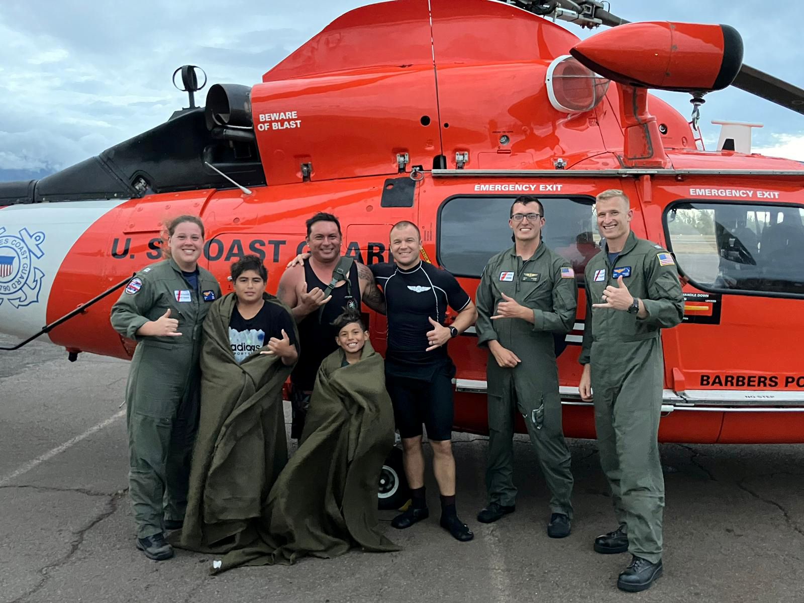 A group poses in front of a helicopter.
