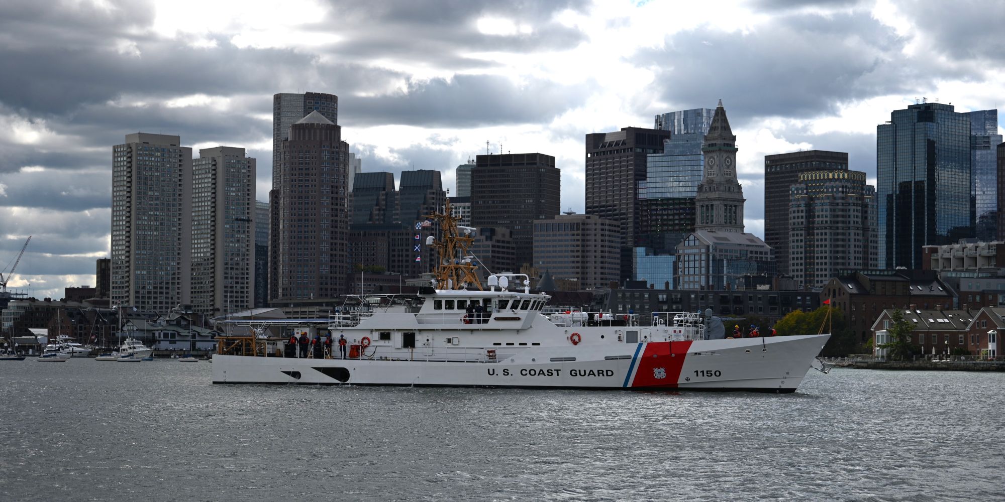 A ship in front of the Boston skyline.