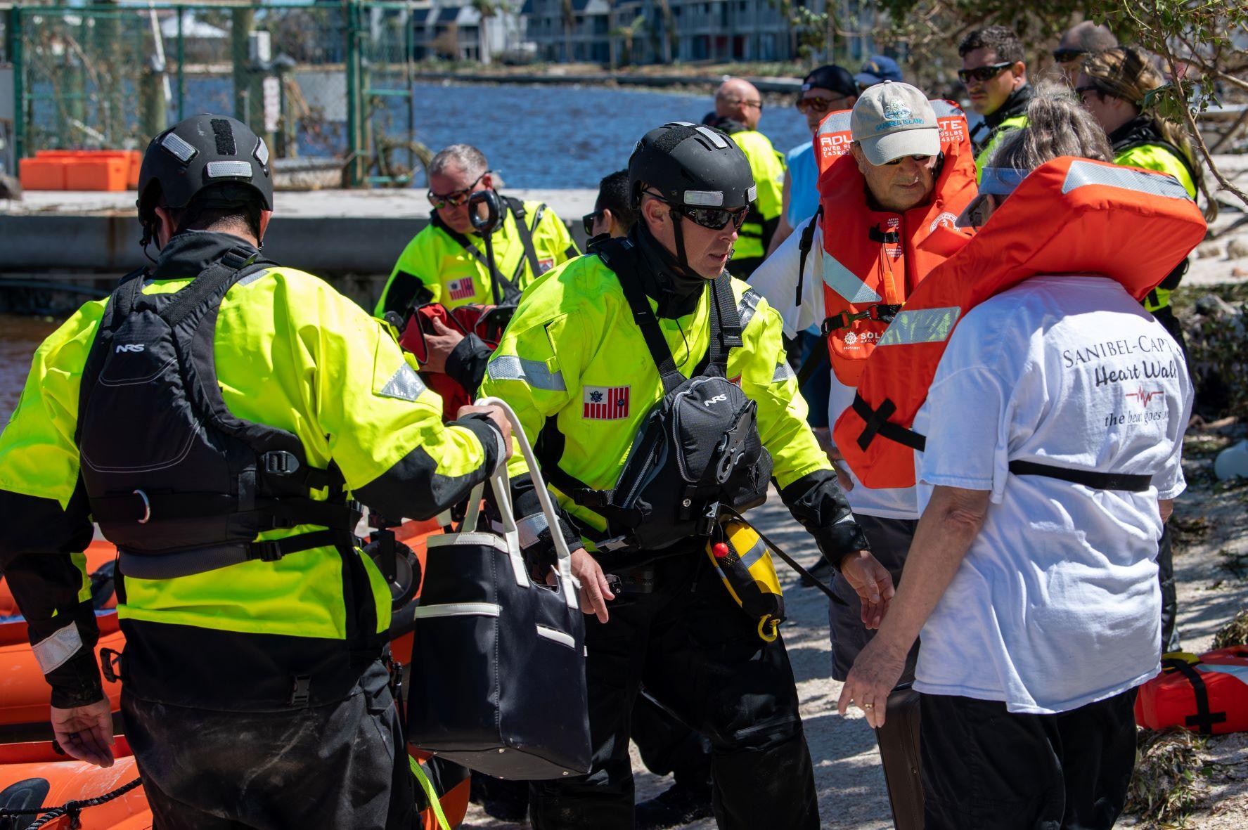 Coast Guard members prepare survivors for transportation to safety by boat in September 2022.