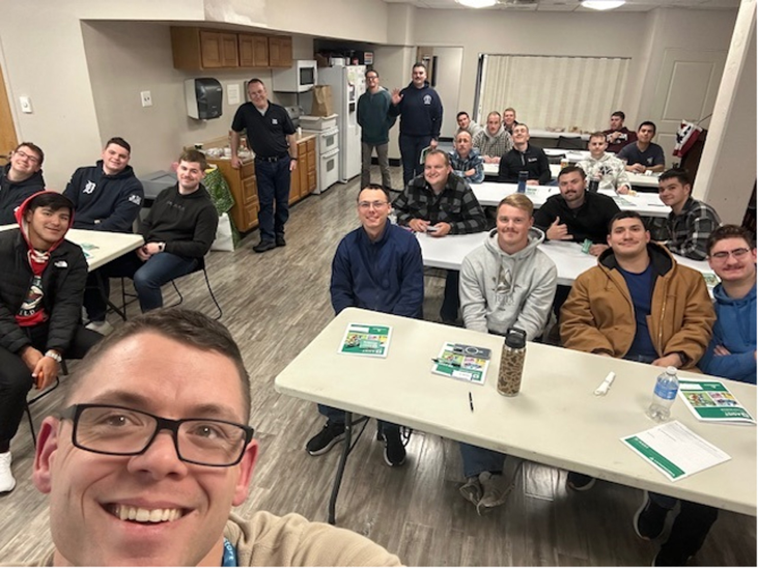 Man takes an "ussie" with a room full of men attending a class.
