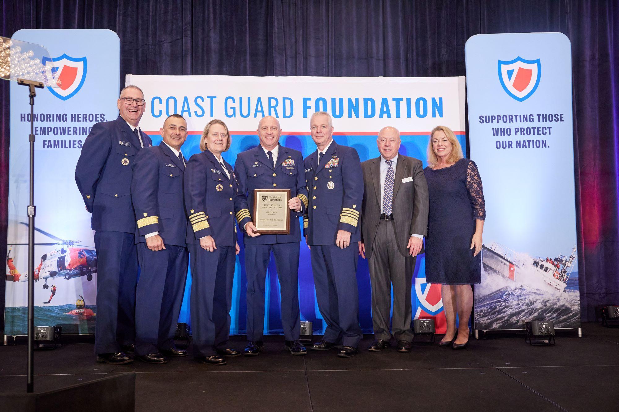 A group of event attendees stands on a stage